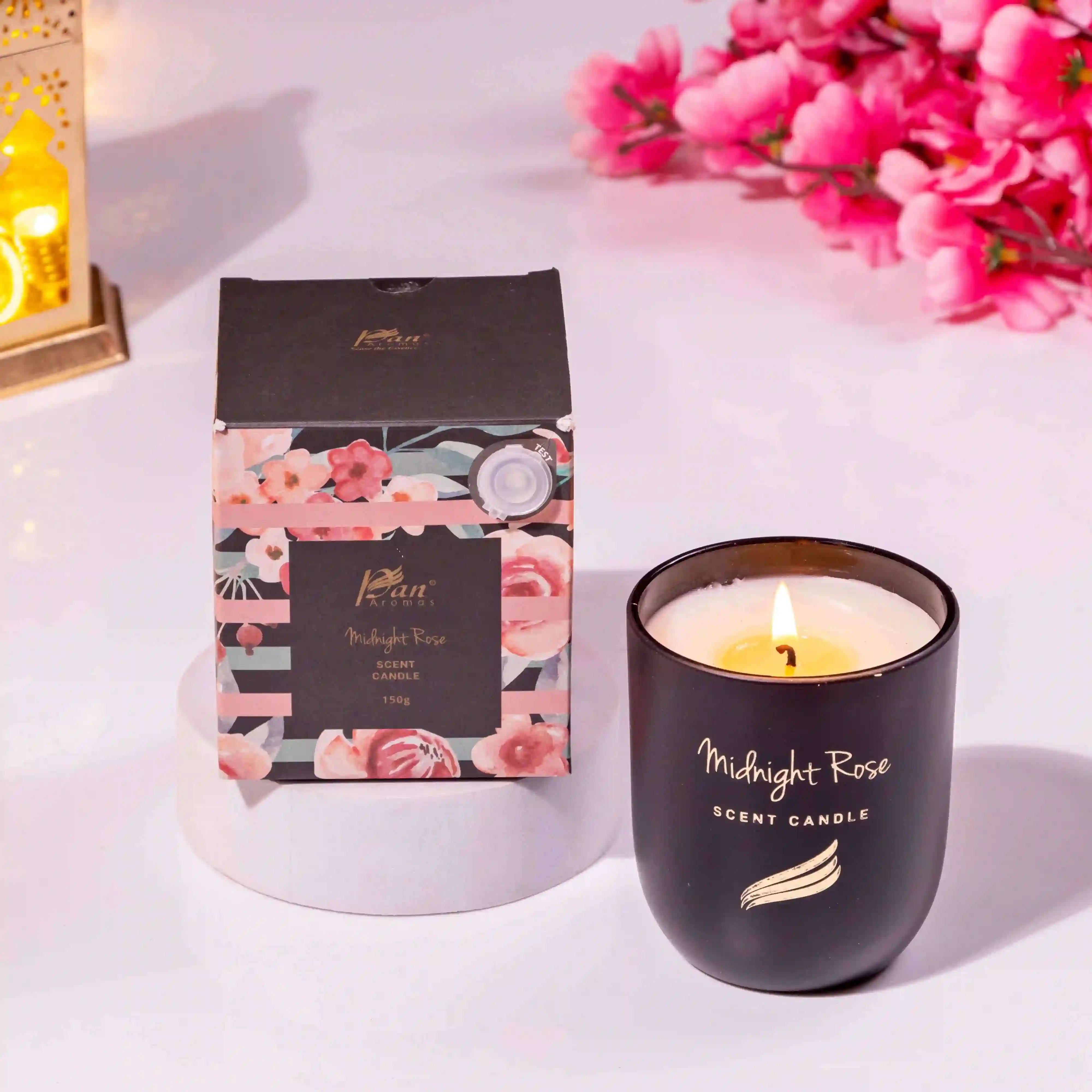 Black scented candle with 'Midnight Rose' branding and packaging on a light background.