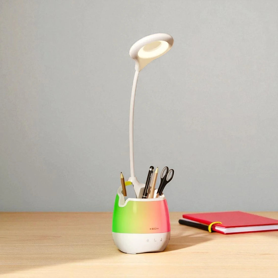 Desk lamp with a colorful base and holder for stationery on a wooden surface.