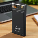 Black portable device with 'Swati' branding on a wooden surface with a laptop in the background