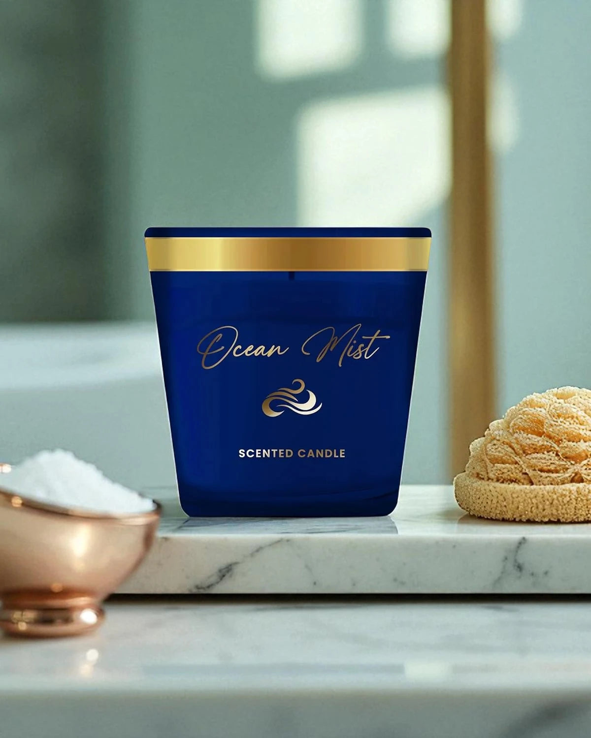 Blue scented candle labeled 'Ocean Mist' on a marble surface with decorative elements.