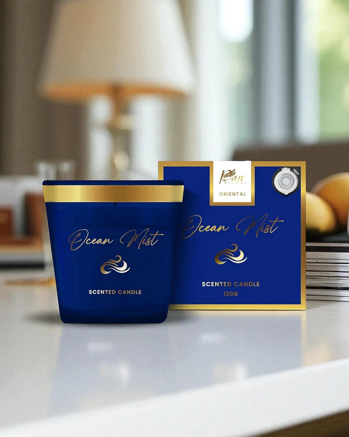 Blue scented candle with gold accents and packaging on a surface.