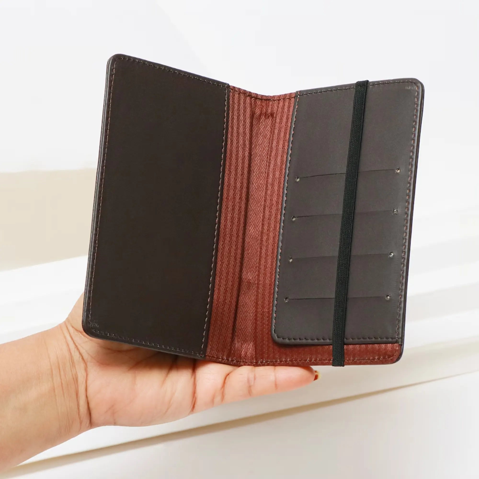 Hand holding a black and brown leather wallet against a light background