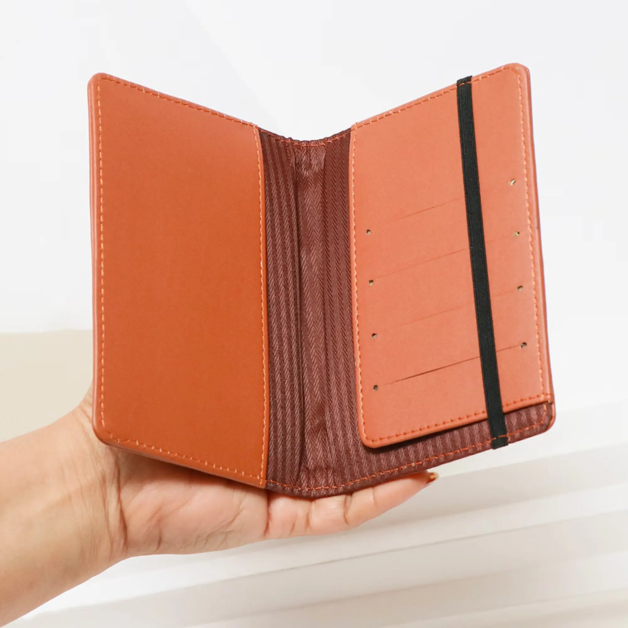 Hand holding a brown leather wallet against a light background