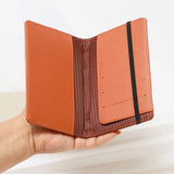 Hand holding a brown leather wallet against a light background