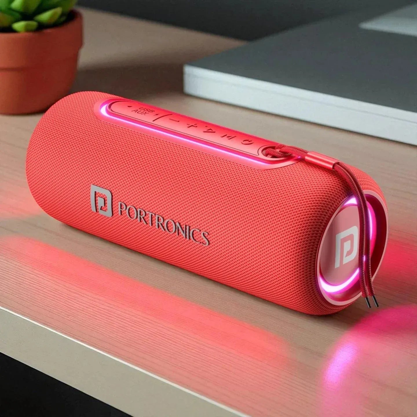 Red Portronics Bluetooth speaker on a wooden surface