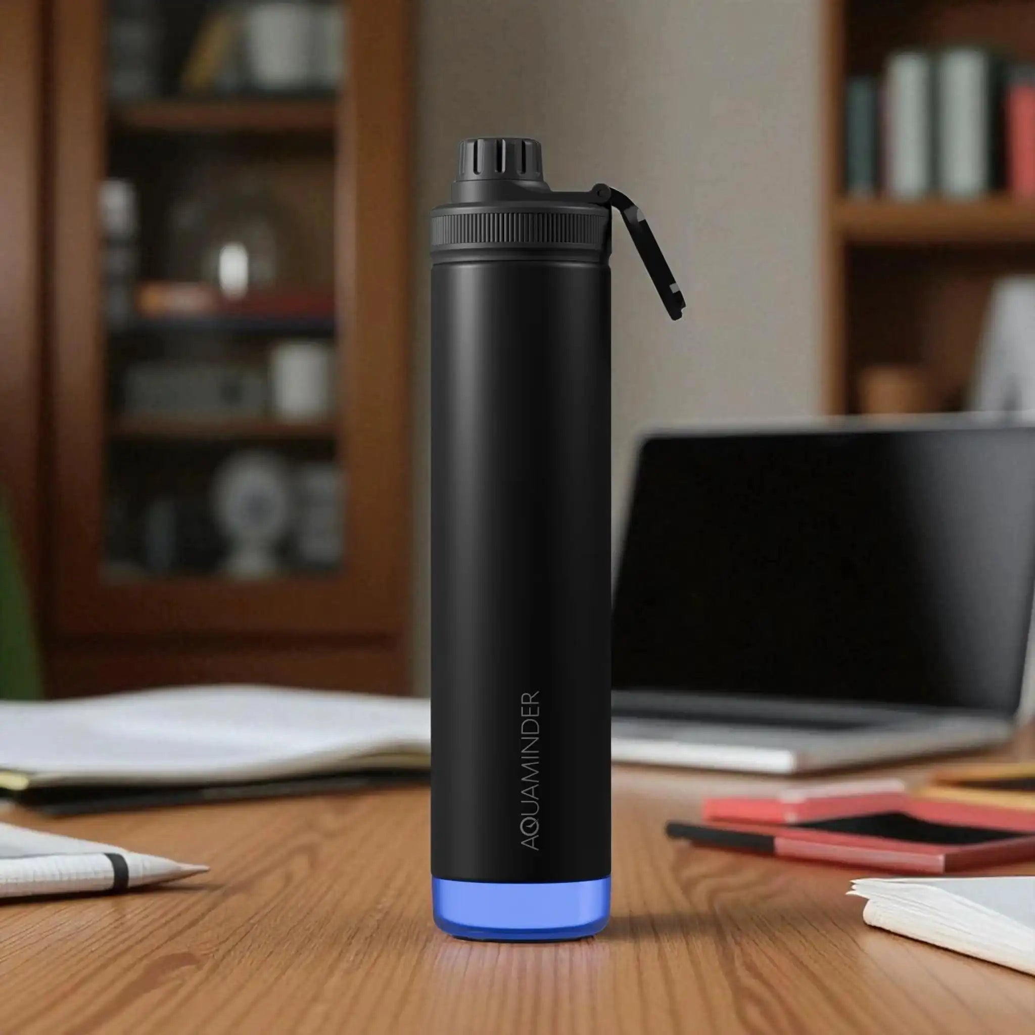 Black water bottle with blue base on a desk in an office setting