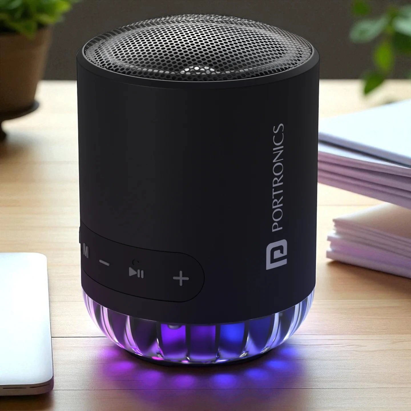 Black Portronics Bluetooth speaker on a wooden surface 