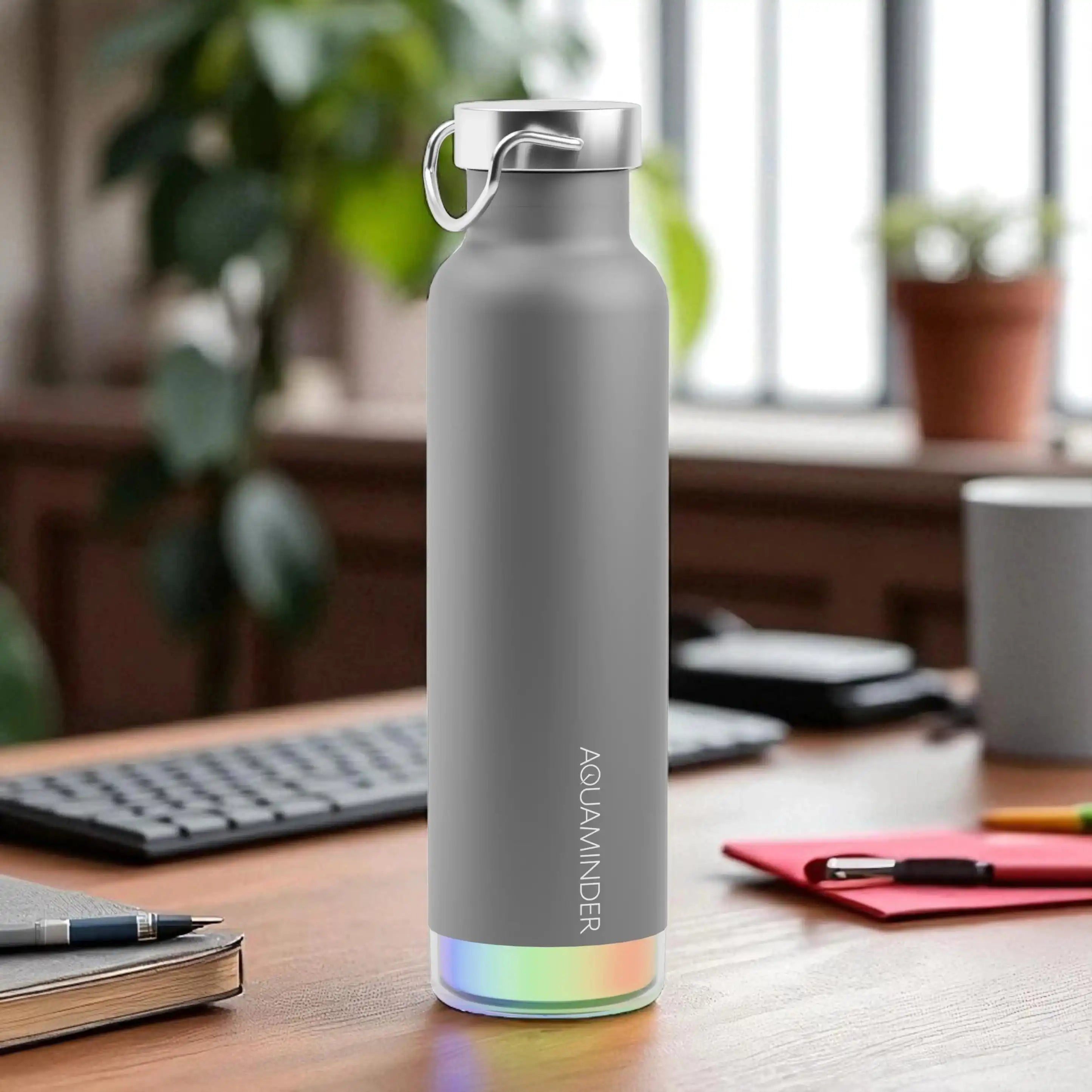 Gray water bottle with colorful base on a desk