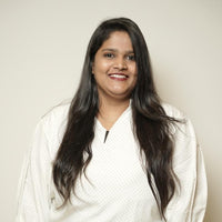 Woman with long dark hair wearing a white top against a plain background