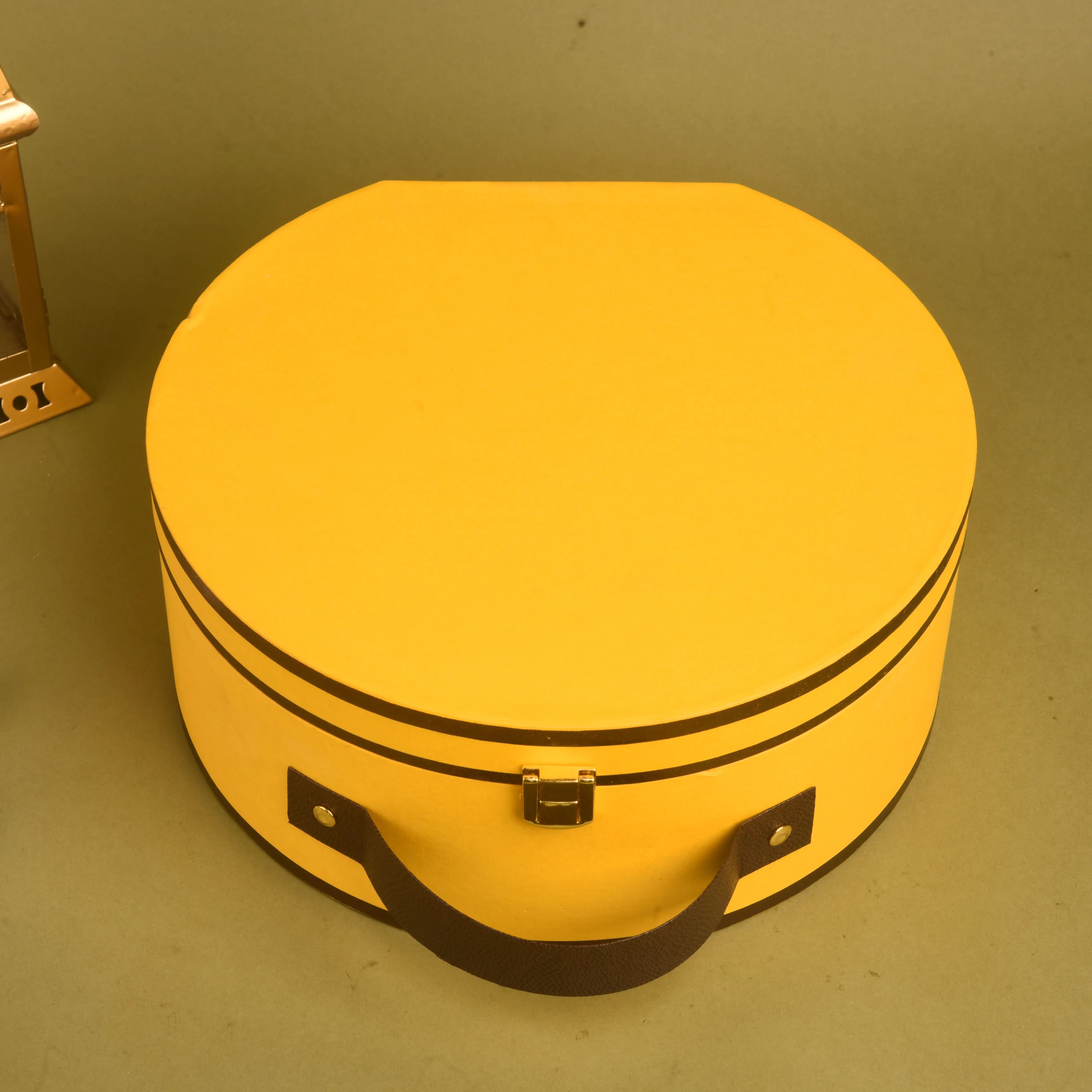 Yellow round suitcase with black straps on a green background