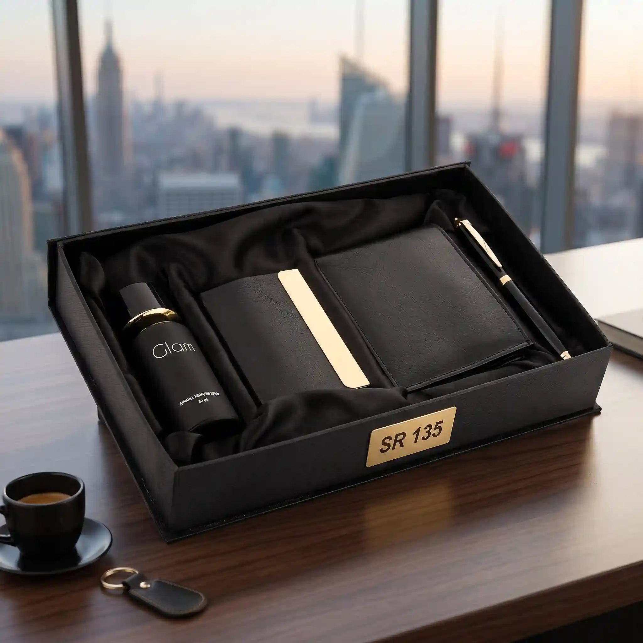 Gift set with black wallet, pen, and other items in a box on a table with a cityscape view.